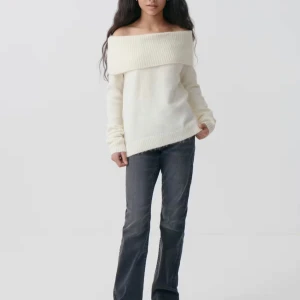Offshoulder stickad tröja i vitt - Säljer en vit offshoulder stickad tröja med bred ribbad kant upptill. Tröjan har lång ärm och är mjuk och skön, perfekt för dig som gillar en chill och snygg stil. Passar dig som vill ha en enkel men ändå trendig look. Ljuset på den sista bilden är lite off. Tröjan är slutsåld! Aldrig använt! 