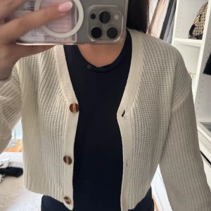 Vit stickad kofta med knappar - Säljer en vit stickad kofta med snygga bruna knappar framtill.