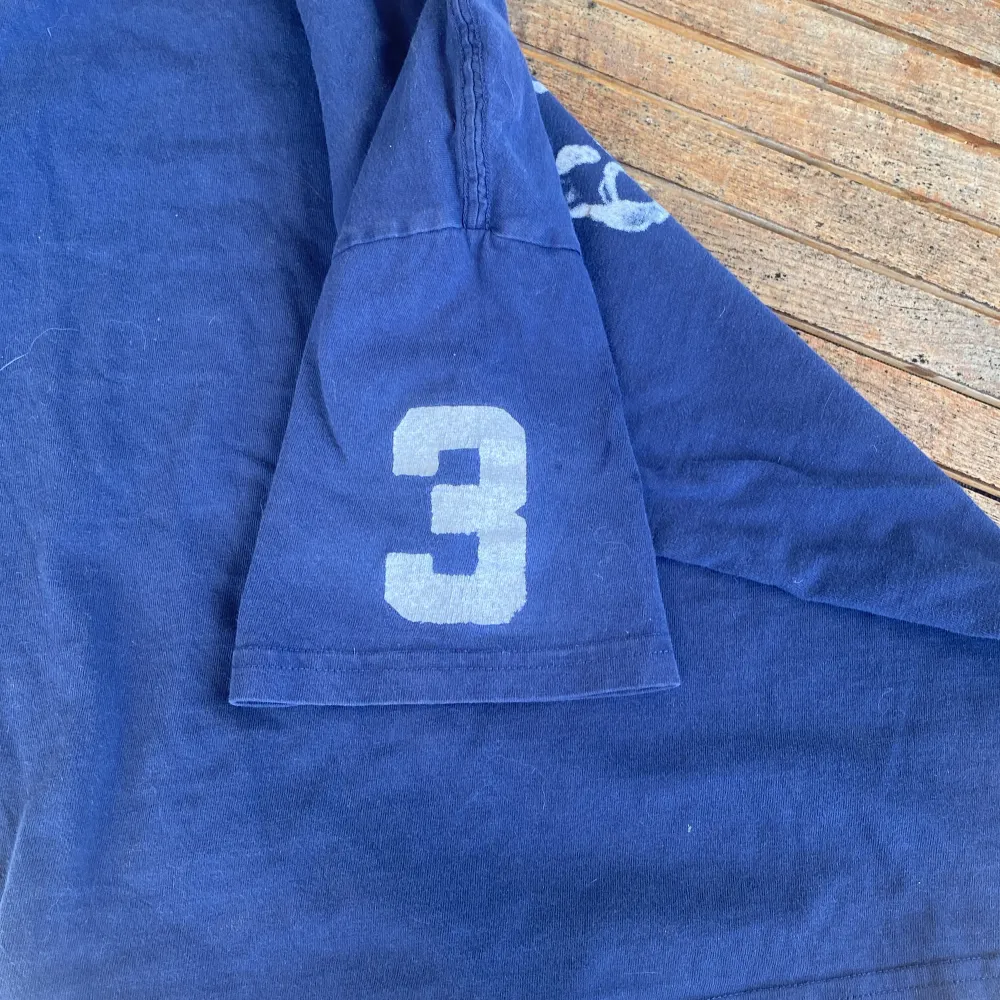 Säljer en blå t-shirt från Ralph Lauren med ett stort tryck av en polospelare och texten 'Polo 67' på framsidan. T-shirten har korta ärmar med siffran '3' tryckt på ena ärmen. Perfekt för en avslappnad stil!. T-paidat.