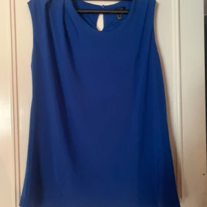 Blå ärmlös topp - Snygg blå ärmlös topp med rund halsringning och en liten öppning bak. Perfekt för en stilren look.