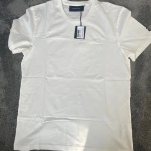 Vit t-shirt från Dolce & Gabbana - Säljer en stilren vit t-shirt från Peak performance. Den har en klassisk rund hals och korta ärmar, perfekt för en minimalistisk look. Passar bra till både jeans och shorts. Perfekt basplagg för garderoben!