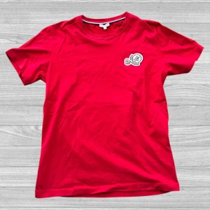 Moncler T-shirt - Säljer en snygg röd t-shirt från Moncler med ett coolt broderat märke på bröstet. T-shirten är kortärmad och gjord i mjuk bomull. Perfekt för en avslappnad stil. Passa på att köpa nu! 🔥