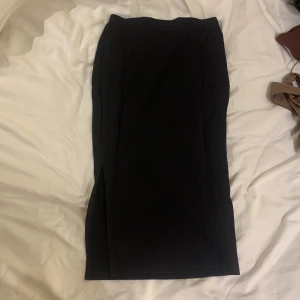 Svart ribbad kjol med slits  - Snygg svart ribbad kjol med en diskret slits. 
