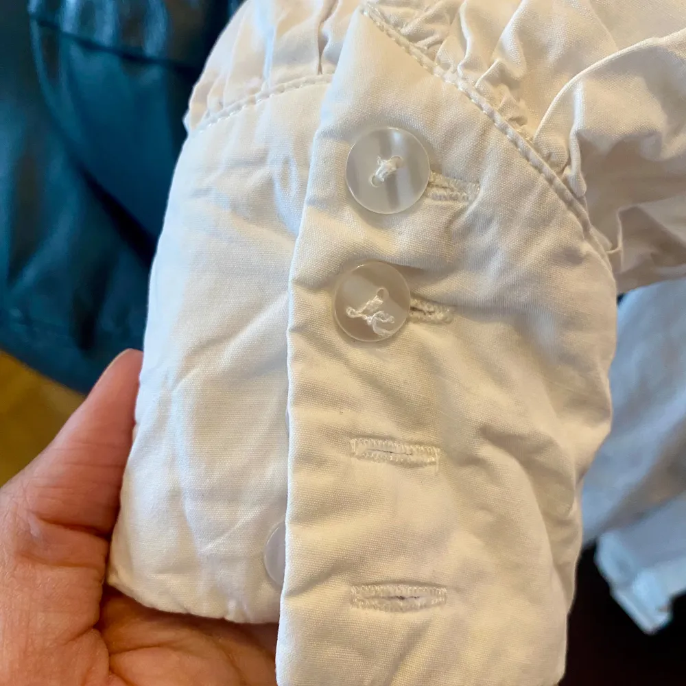 Säljer en stilren vit blus från Shein med klassisk krage och knappar framtill. Blusen har långa ärmar med knappdetaljer vid ärmsluten. Perfekt för en chic och enkel look.. Paidat.