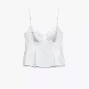 Vit korsett-topp med knappar - Säljer en stilren vit korsett-topp med smala axelband och knappar framtill. Toppen har en figurnära passform med volang effekt, och  är perfekt för en chic look. 