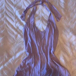 Lila halternecktopp - Säljer en lila halternecktopp med u-ringning och smockdetaljer i ryggen. Perfekt för sommarens alla tillfällen. Toppen har en mjuk och flödande passform.