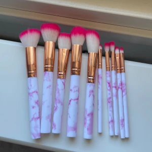 Set med sminkborstar med marmormönster - Snyggt set med sminkborstar med vita och rosa marmormönstrade handtag och roséguld detaljer. Borstarna har täta, mjuka borst i vitt och rosa. Perfekt för både ansikts- och ögonsminkning.