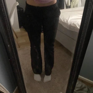 Svarta byxor från BikBok - Snygga svarta kostymbyxor från BikBok med en klassisk design. De har en rak/bootcut passform och är perfekta för en stilren look. Byxorna har en liten skada på ena benet som kan fixas med lite kreativitet.