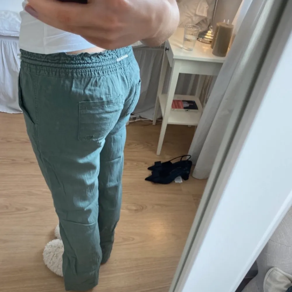 Säljer ett par gröna byxor från Roxy med snörning i midjan. Byxorna har en avslappnad passform och är perfekta för en chill dag. De har fickor både fram och bak, vilket gör dem praktiska och snygga.. Farkut & Housut.