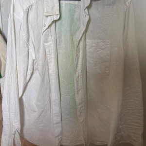 Vit skjorta från H&M - Säljer en vit långärmad skjorta från H&M i relaxed fit. Skjortan har en klassisk krage och en bröstficka. Perfekt för en stilren och avslappnad look.