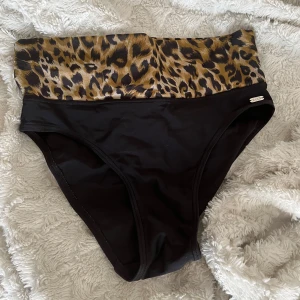 Svart och leopardmönstrad bikiniunderdel - Säljer denna bikiniunderdel med hög midja från C&A. Den har en stilren svart bas med en bred leopardmönstrad kant upptill.🐆💞