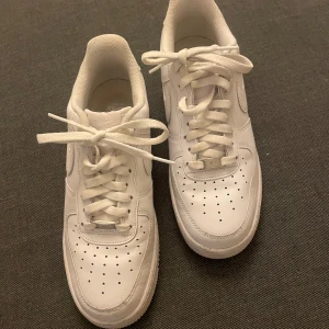Vita Nike Air Force sneakers - Säljer ett par klassiska vita Nike Air Force sneakers. Skorna har en rund tå och snörning framtill. Perfekta för en stilren look och passar till det mesta.