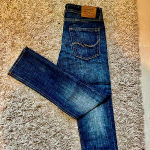 Blå jeans från Jack & Jones - Snygga blå jeans från Jack & Jones med en slim passform. De har en klassisk femficksdesign och en lätt slitning på framsidan för en trendig look. Perfekta för en avslappnad stil.