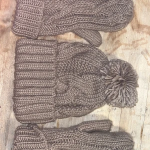 Brun stickad mössa med tofs från odd molly  - Säljer en mysig brun stickad mössa med en stor tofs på toppen. Mössan har ett flätmönster och en bred ribbad kant som ger extra värme och stil. Perfekt för kalla dagar! Nypris 500