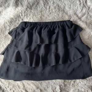 Svart volangkjol från PrettyLittleThing - Snygg svart kortkjol från PrettyLittleThing med flera lager av volanger🩷