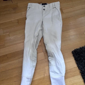 Vita ridbyxor från CRW LÄS👇 - Säljer ett par vita ridbyxor från CRW. Byxorna har en klassisk design med knappar och dragkedja framtill. I storlek 150. Dom är lika mycket använda som kavajen jag säljer så 4 gånger ungefär. Och jag tvättar såklart allt innan jag skickar! Kan även tänka mig att köpa ridbyxorna och kavajen tillsammans, vid intresse för det kan ni skriv så diskuterar vi pris m.m. Helskodda