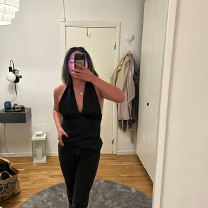 Svart halterneck topp - Snygg svart halterneck topp med djup urringning. Perfekt för en kväll ute eller en fest. Från nakd i storlek S