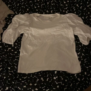 Vit blus från Kappahl - Säljer en stilren vit blus från Kappahl i storlek XS. Blusen har puffiga trekvartsärmar och en rund halsringning. Perfekt för en elegant look.