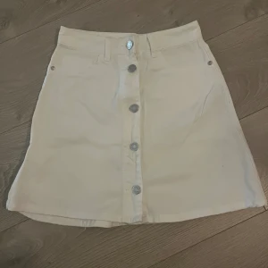 Vit jeanskjol med knappar  - Snygg kort jeanskjol med silvriga knappar och fickor där bak 🌸jättefint skick, använd fåtal gånger. Rökfritt hem! Skicka meddelande vid frågor/fler bilder 🩷