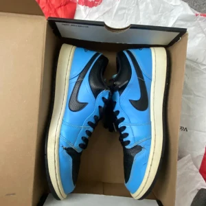 Nike Air Jordans i blått och svart - Snygga Nike Air Jordans i en fräsch blå och svart färgkombination. Skorna har en klassisk design med snörning och rund tå. Perfekta för dig som vill ha en stilren look med en sportig touch.