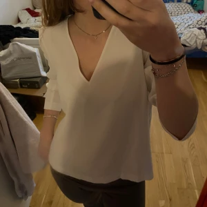 Vit v-ringad blus - Säljer en stilren vit blus med v-ringning och trekvartsärmar. Perfekt för en elegant och avslappnad look.