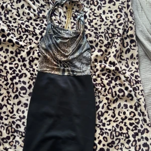 Leopardmönstrad klänning från Progress - Snygg leopardmönstrad klänning från Progress med halterneck och öppen rygg. Klänningen har en tight passform och är perfekt för en utekväll. Den har ett coolt mönster i olika nyanser av brunt och svart.