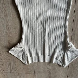 Vit ribbad ärmlös topp - Säljer en stilren vit ribbad topp med ärmlös design.lite genomskinlig men ingen man tänker på. Toppen har en mjuk och stretchig känsla som gör den bekväm att bära.🩷🩷