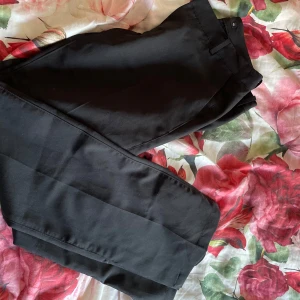 Svarta kostymbyxor från BikBok - Snygga svarta kostymbyxor från BikBok i storlek 40. Byxorna har en klassisk design med raka ben och diskreta fickor baktill. Perfekta för en stilren look.