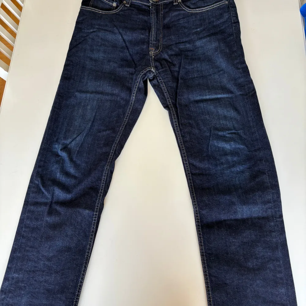 Säljer ett par mörkblå jeans från Dressmann i regular fit. Byxorna har en klassisk femficksdesign och är tillverkade i slitstarkt denim. Perfekta för en avslappnad stil.. Farkut & Housut.
