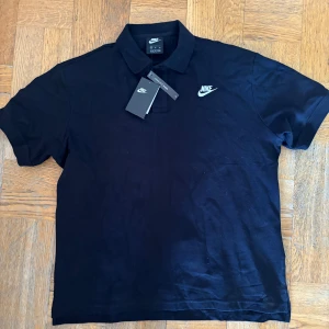 Svart pikétröja från Nike - Säljer en svart pikétröja från Nike med klassisk krage och korta ärmar. 