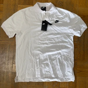 Vit pikétröja från Nike - Säljer en klassisk vit pikétröja från Nike med broderad logga på bröstet. Ej äkta, priset går att diskutera vid smidig affär. 