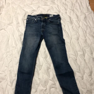 Blå jeans från Jack & Jones - Snygga blå jeans från Jack & Jones med en tapered passform. De har en klassisk femficksdesign och en bekväm midwaist. Perfekta för en avslappnad stil.