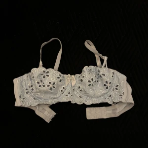 Ljusblå spets-bh med blommönster - Säljer en elegant ljusblå bh från 90-talet. Mamma har använt den få gånger med vacker spets och blommönster. Den har justerbara axelband och en söt rosett framtill. Perfekt för att känna sig extra fin.