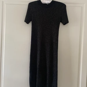 Svart glittrig klänning från Zara - Snygg svart glittrig klänning från Zara med korta ärmar. Perfekt för en kväll ute eller en speciell tillställning. Klänningen har en elegant och stilren design som passar många tillfällen.