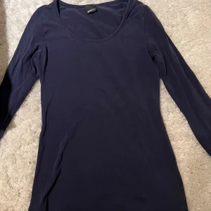 Mörkblå långärmad topp från Gina Tricot - Säljer en stilren mörkblå långärmad topp från Gina Tricot. Perfekt för lager-på-lager eller att bära som den är. Tröjan har en rund halsringning.