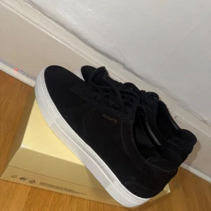 Axel Arigato  - Snygga svarta sneakers i mocka från miinto med vit sula. Skorna har en stilren design med snörning och diskret logga pa sidan. Perfekta för en trendig look. Nypris 2518kr. Allt på bilderna ingår. Kvitto fins med 