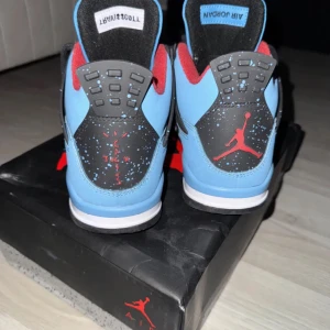 Nike Air Jordans 4 retro travis Scott’s blå svart - Snygga Nike Air Jordans i en fräsch blå färg med svarta och röda detaljer. Skorna har en ikonisk design med snörning och en rund tå. Perfekta för dig som vill ha en stilren look med en sportig touch.