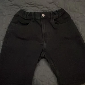 Svarta shorts från H&M - Snygga svarta shorts från H&M med knapp och dragkedja framtill. De har både fram- och bakfickor, vilket gör dem praktiska för vardagsbruk. Perfekta för en avslappnad stil.