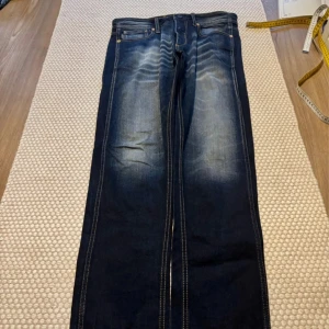 Mörkblå jeans - mörkblå jeansbyxor med ljusa slitningar och femficksdesign.