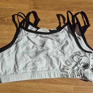 2 st vita Snoopy bh-toppar XS - Säljer två söta vita linnetoppar med Snoopy-tryck. Topparna har svarta kanter och tunna justerbara axelband. Perfekt för en avslappnad stil med en touch av nostalgi från 2000-talet. 🐶 Topparna är helt oanvända med orginalapparna kvar. Kommer från ett konkurslager. Se även mina andra annonser för möjlighet till bundle/paket med rabatt och samfrakt.