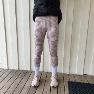Beige mönstrade leggings från SOC - Säljer ett par beige leggings från SOC med ett subtilt bladmönster. De är tillverkade i ett stretchigt material som passar perfekt för träning. Leggingsen har en tight passform och är midwaist.jätte fina spring tights