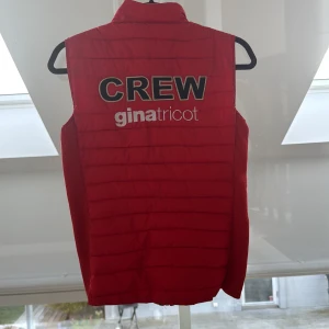 Röd dunväst från Gina Tricot - En super cool väst från Gina tricot Falsterbo horse show CREW. Den är röd med resår på sidorna. Det står CREW på ryggen. Den är i storleken S