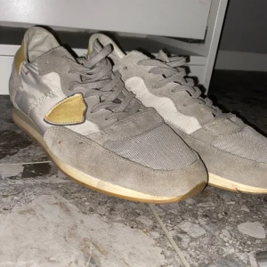 Philippe model trainers - Snygga grå sneakers med en unik gul detalj på sidan. Skorna har snörning och en rund tå, vilket ger en klassisk look. Perfekta för en avslappnad stil. Bra skick inga speciella defekter.