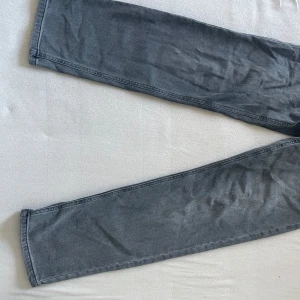 Grå jeansbyxor - Snygga grå jeansbyxor med en klassisk design. Byxorna har en rak passform och är perfekta för en avslappnad stil. De har bakfickor och en elastisk midja för extra komfort.