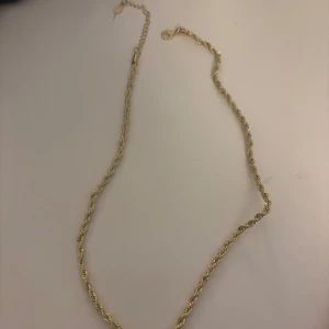 Guldplaterat halsband 18k - Elegant guldfärgat halsband med en vriden kedjedesign. Perfekt för att lägga till en touch av stil till vilken outfit som helst. Lätt att matcha med andra smycken.