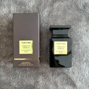 Tom Ford Tobacco Vanille Eau de Parfum 100 ml - Exklusiv parfym från Tom Ford med en rik och varm doft av tobak och vanilj. Flaskan är elegant och svart med en guldig etikett. Perfekt för den som vill ha en lyxig och sofistikerad doftupplevelse. Kvitto tillkommer!