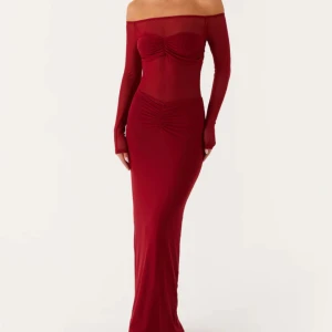 Vinröd långklänning - Elegant vinröd långklänning med offshoulder-design och långa ärmar. Klänningen har en figurnära passform och stilrena detaljer som framhäver silhuetten.