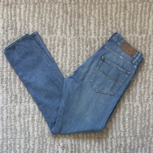 Blå Pistolero jeans från Tiger of Sweden - Snygga blå jeans från Tiger of Sweden med klassisk femficksdesign. De har en knappgylf och är tillverkade i ett mjukt denimtyg. Perfekta för en stilren look.