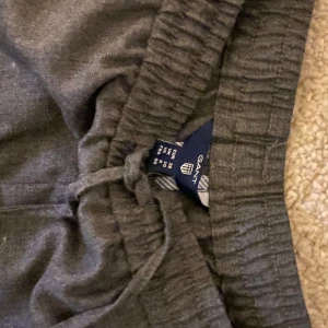 Grå byxor från Gant - Säljer ett par grå kostymbyxor från Gant med elastisk midja och snörning. Byxorna har en avslappnad passform och är perfekta för en bekväm stil. Skickar gärna bild på om så önskas. 