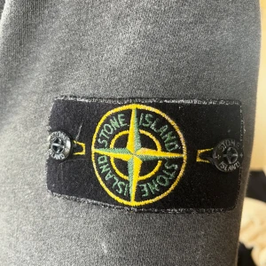 Grå sweatshirt från Stone Island - Stentvättad stone Island tröja köpt på NK. De vita fläckarna är ej slitage utan en del av stentvätten. Är en medium men passar snyggt på mig som vanligtvis har small